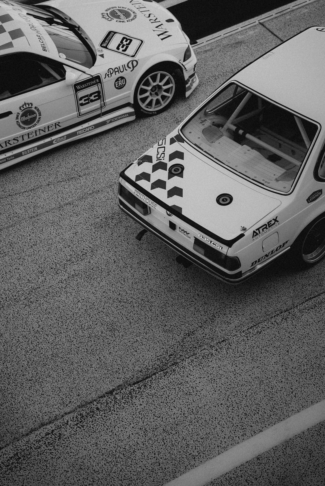 Twee klassieke BMW-racewagens van bovenaf gefotografeerd, in zwart-wit